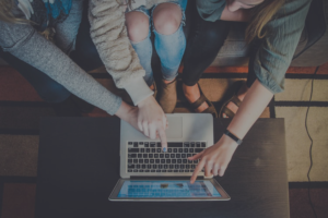 Three people are using a laptop on the table.