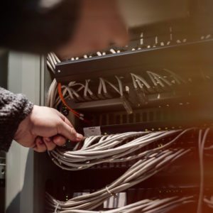 A person is working on some wires in an electrical box.