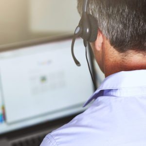 A man with headphones on looking at a computer screen.