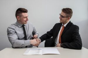 Two men shaking hands over a table.