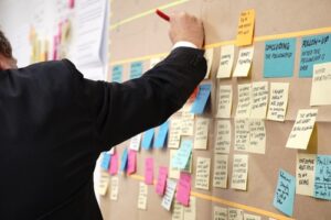 A person writing on post it notes on a wall.