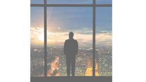 Silhouette of man viewing city at sunset.