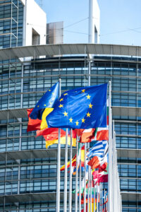 European Union flags waving outside building.