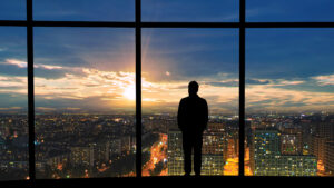 Silhouette of man viewing city sunset.