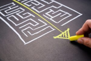 Hand draws solution to chalk maze.